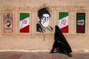 Một người phụ nữ đi ngang qua bức tranh tường mô tả cố lãnh đạo tối cao của Iran, Ali Khamenei, tại Quảng trường Valiasr ở trung tâm Tehran [Atta Kenare/AFP]